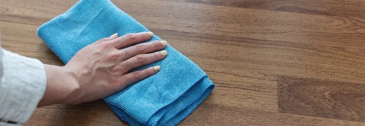 Hand reinigt Holzboden mit Tuch